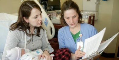 Shelly Bennett, of Lawrence, holds her 1-day-old daughter, Madeline, and goes over information on postpartum depression with Amy Johnson, a registered nurse at Lawrence Memorial Hospital. At the LMH Birthing Center, discharge nurses provide new parents with information on postpartum mental health symptoms to be aware of.