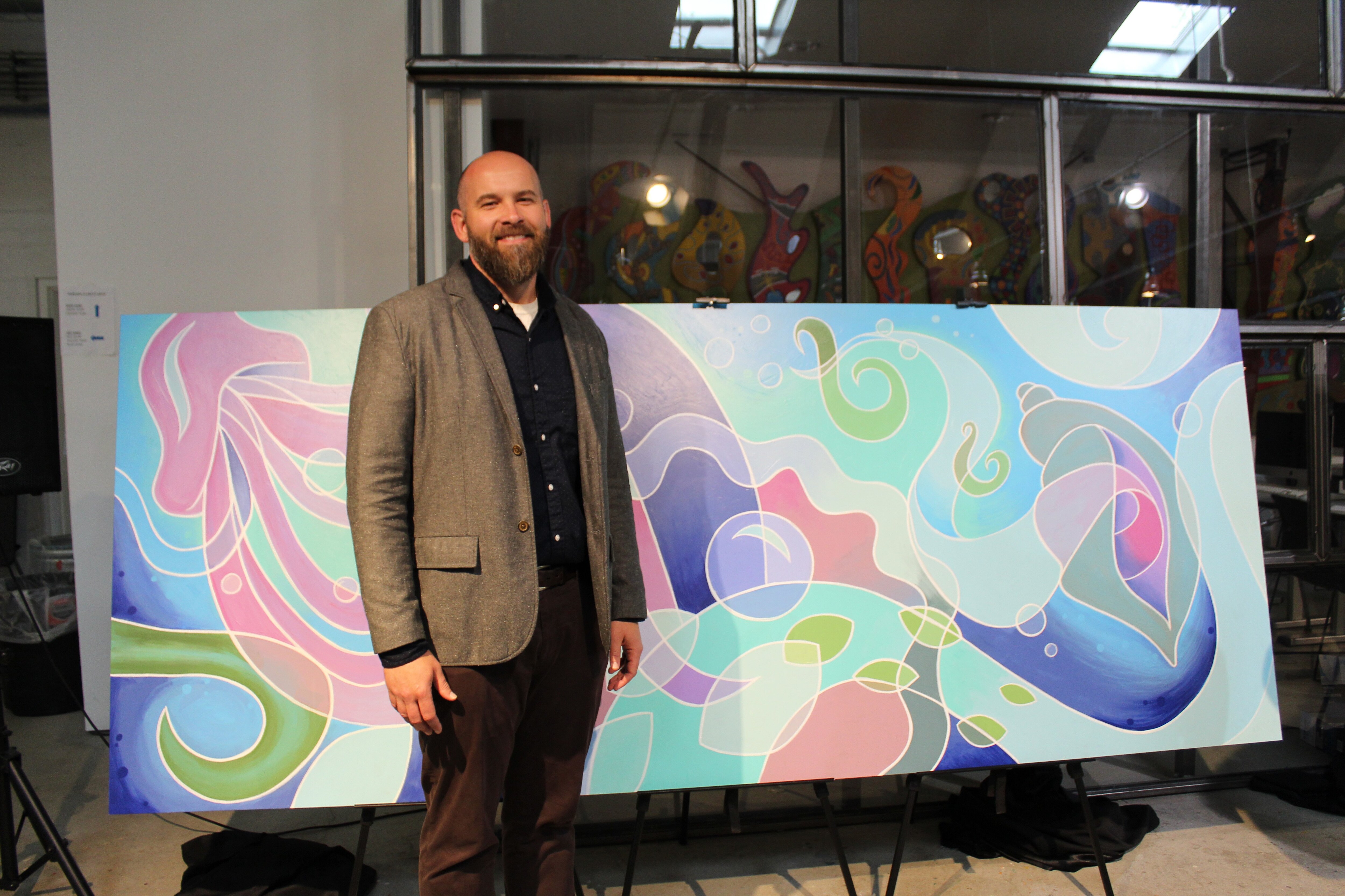 Derrick Hurst stands next to mural created by Van Go artists