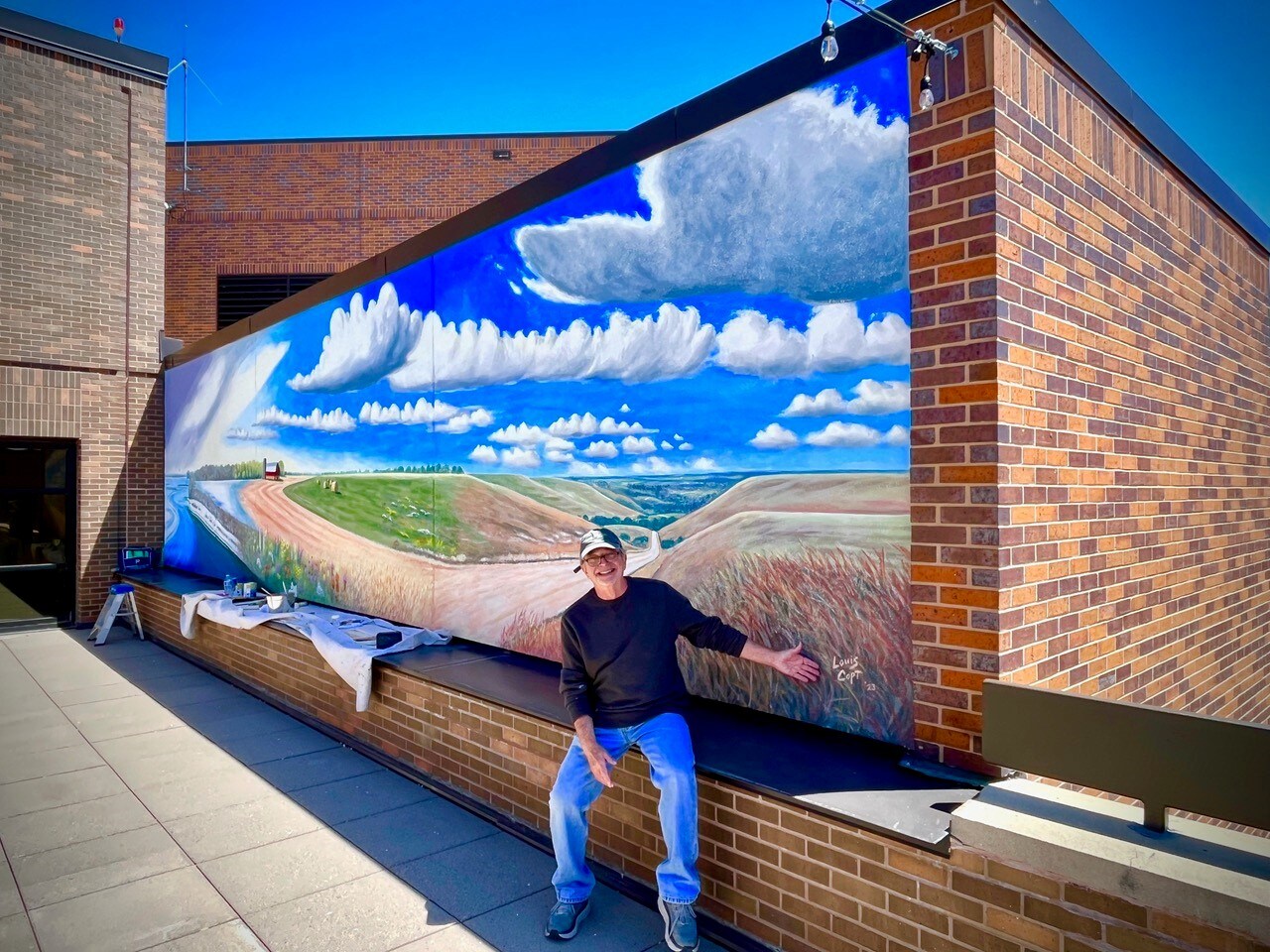 Louis Copt poses in front of his mural