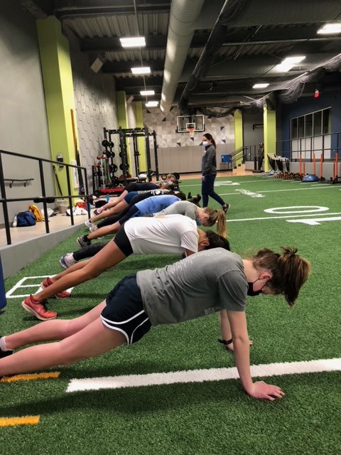 Campbell Helling, Emma Roman Nose and Hannah Motsinger perform a plank exercise