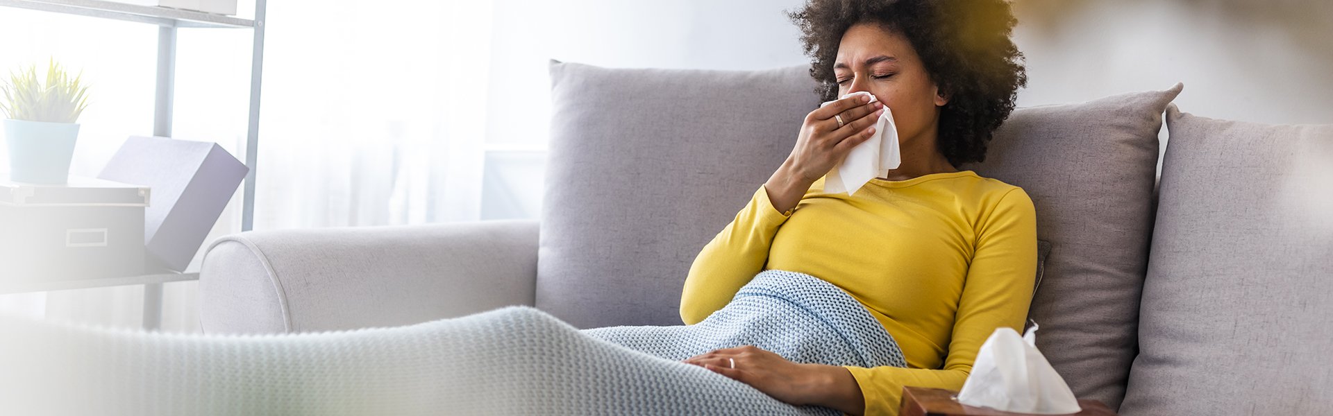 Photo of sick patient on couch with tissues